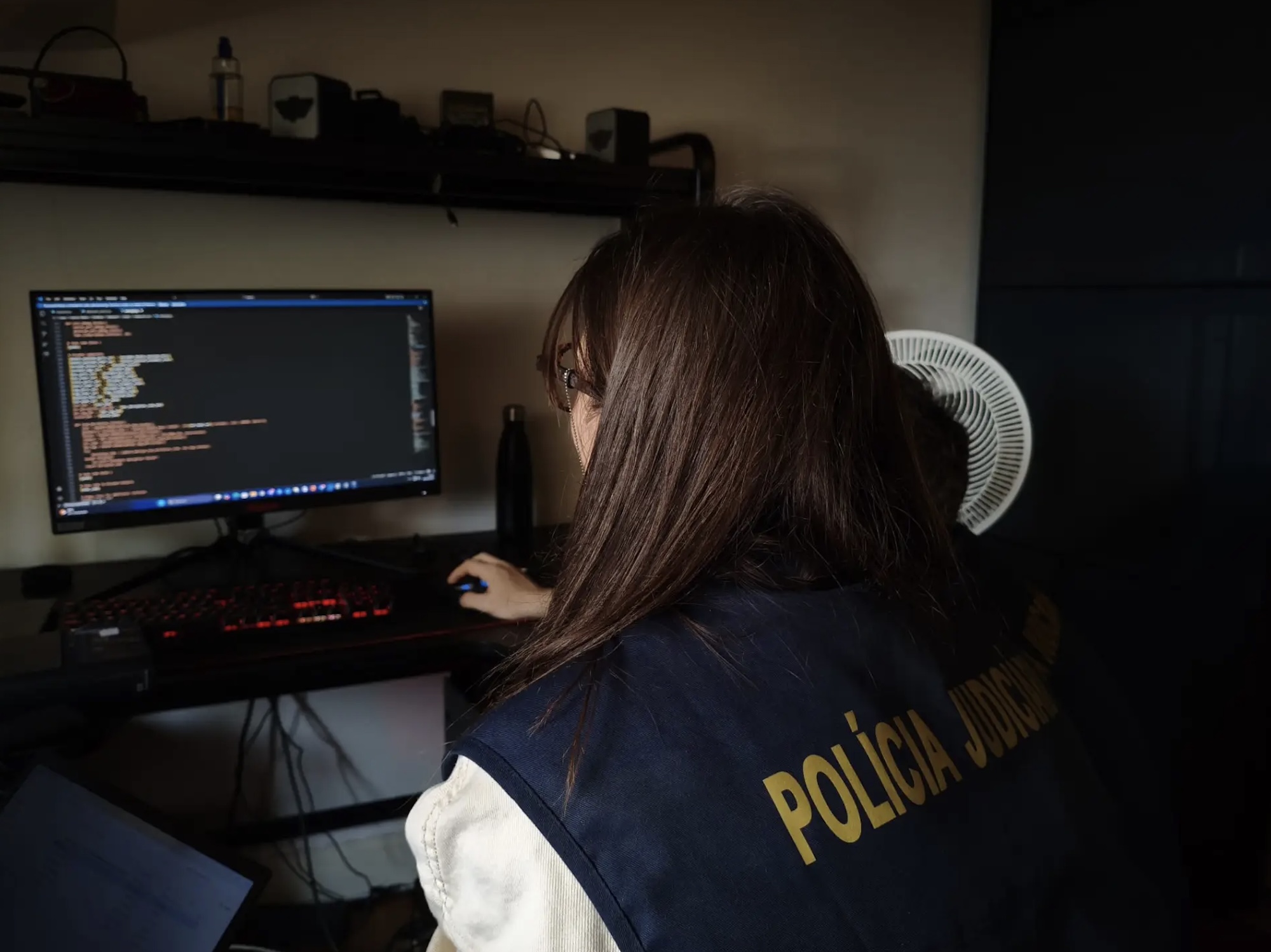 a photo of a European police officer examining a computer at the home of a forum member.